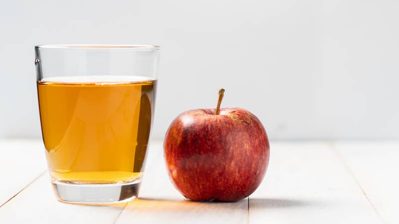 apple juice in a glass next to an apple