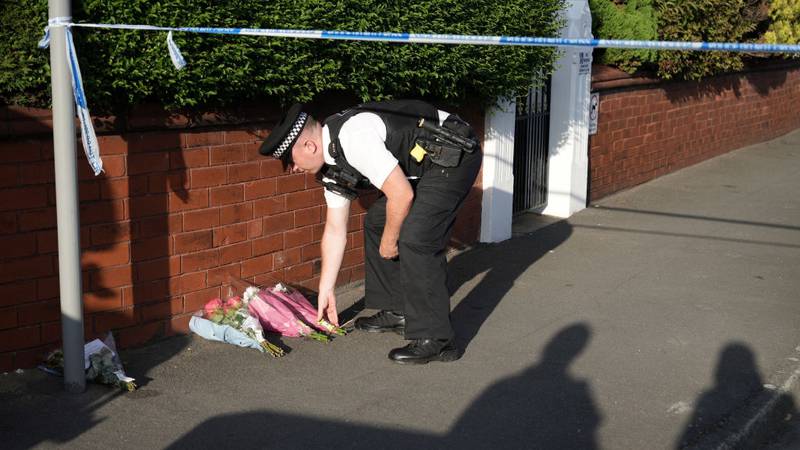 Police officer lays flowers at stabbing scene.